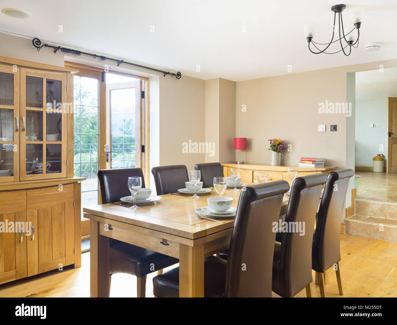 Un tavolo da pranzo insieme per il pranzo in una confortevole sala da pranzo con una vista attraverso la cucina. Foto Stock