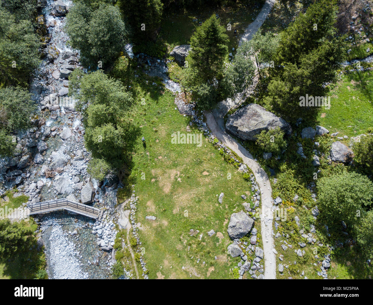 Vista aerea di un ponte di legno e un fiume in Val di Mello, una verde vallata circondata da montagne di granito e boschi. Italia Foto Stock