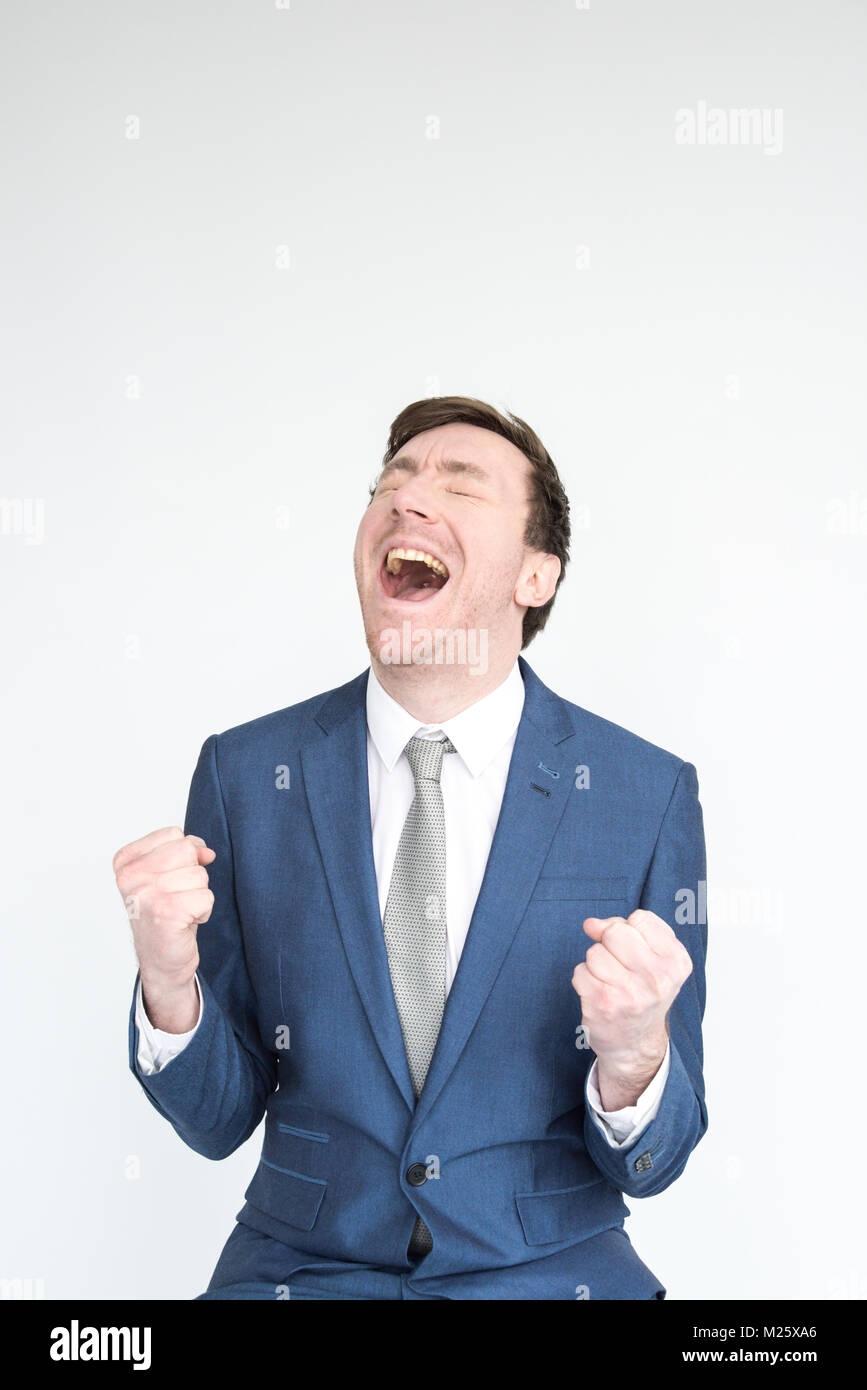 Un molto eccitato, ben vestito uomo in una tuta punzoni l'aria in trionfo al raggiungimento di un obiettivo. ritratto isolato su sfondo bianco Foto Stock