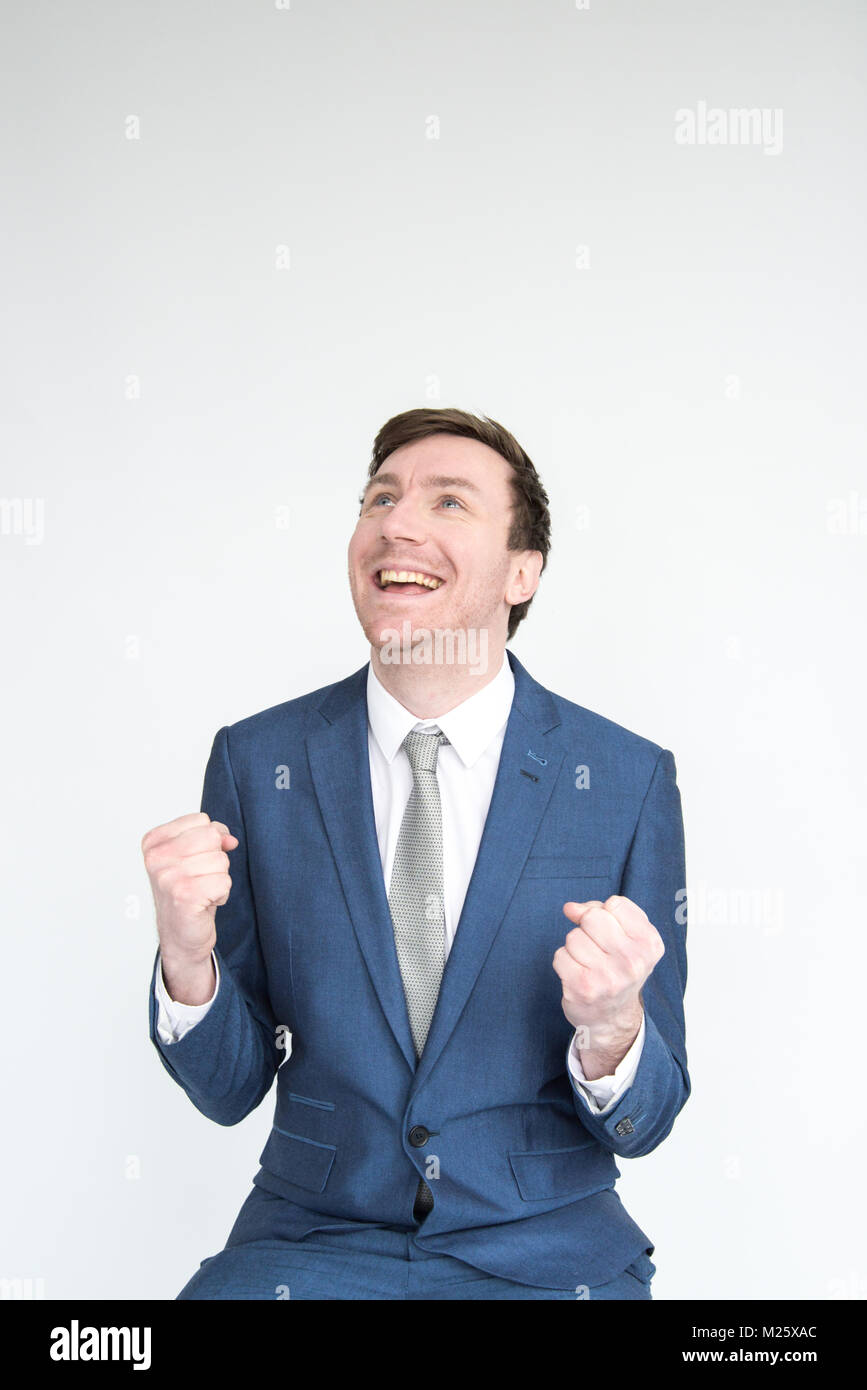 Un molto eccitato, ben vestito uomo in una tuta punzoni l'aria in trionfo al raggiungimento di un obiettivo. ritratto isolato su sfondo bianco Foto Stock