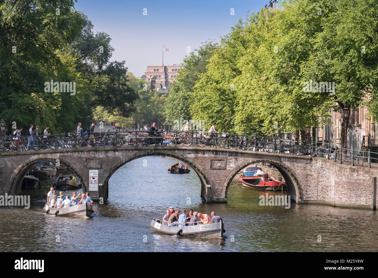 Le imbarcazioni turistiche passando sotto il ponte di Amstel, in corrispondenza della giunzione del fiume Amstel e Herengracht canal, Amsterdam, Paesi Bassi. Foto Stock