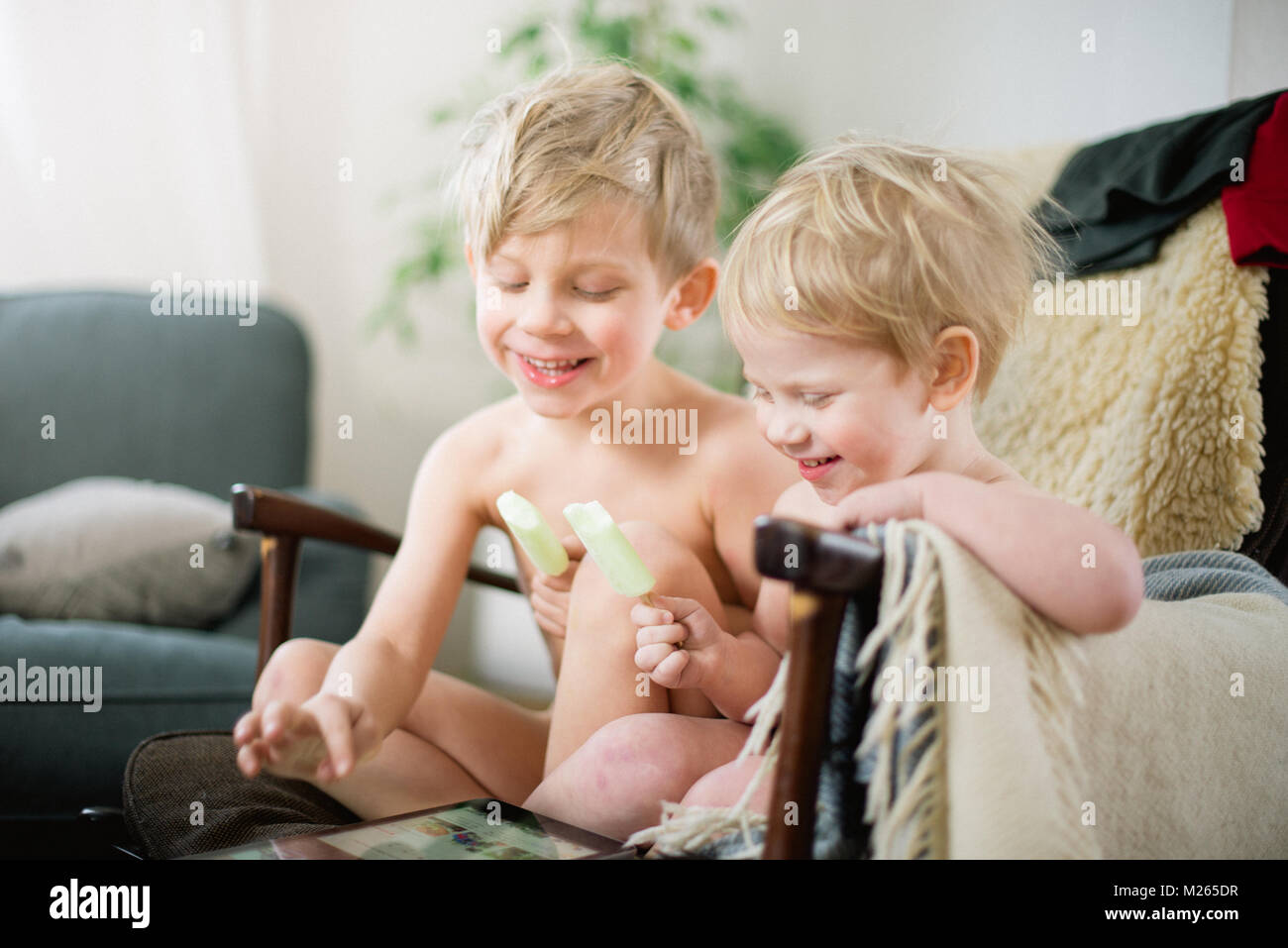 Due fratelli a mangiare il gelato in poltrona reclinabbile mentre godendo Internet movie clip sul tablet. Foto Stock