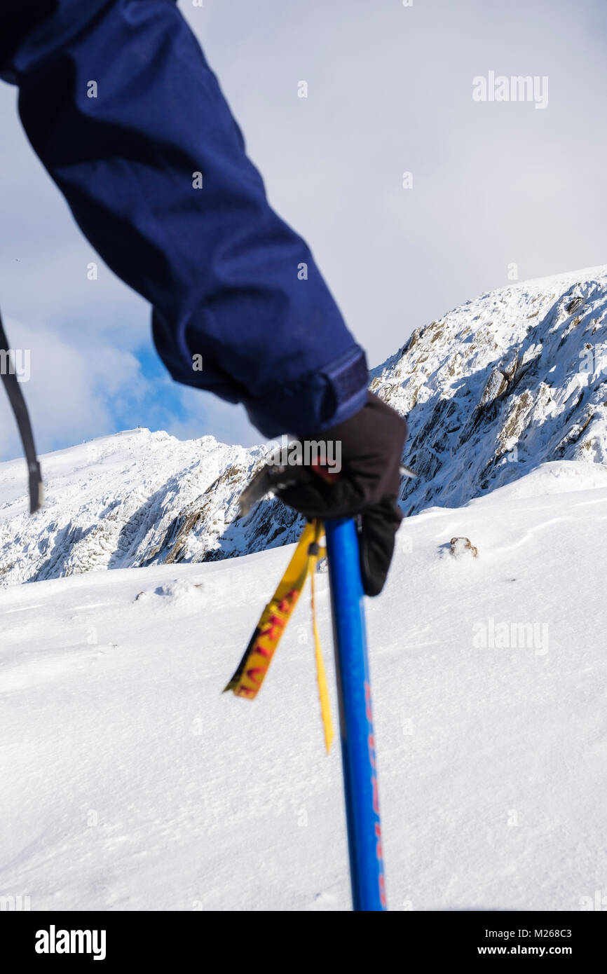 Escursionista tenendo una piccozza in mano le escursioni su Rhyd Ddu percorso con vista di Mt Snowdon in inverno la neve nel Parco Nazionale di Snowdonia Gwynedd Wales UK Gran Bretagna Foto Stock