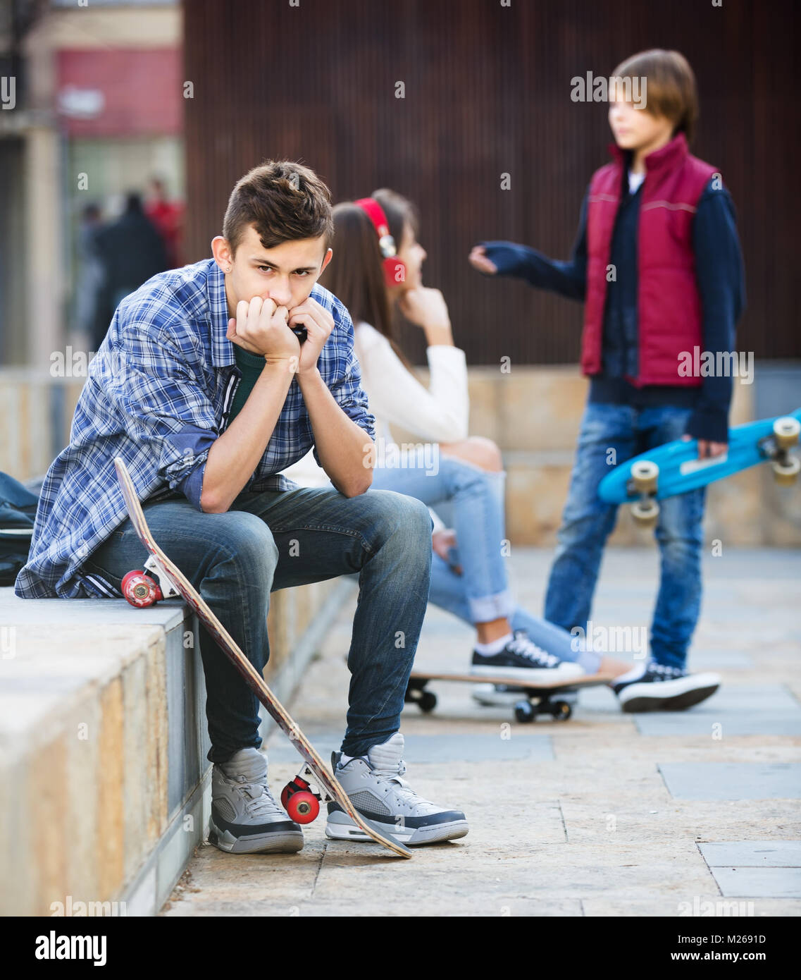 Envy teen maschio seduta da parte della ragazza parlando con il ragazzo in città Foto Stock
