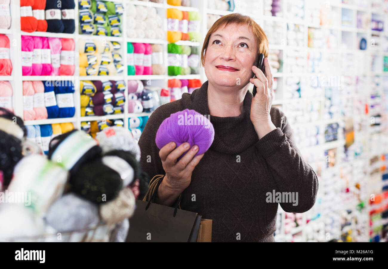 Sorridente donna senior con lo smartphone dopo lo shopping in ricamo shop Foto Stock