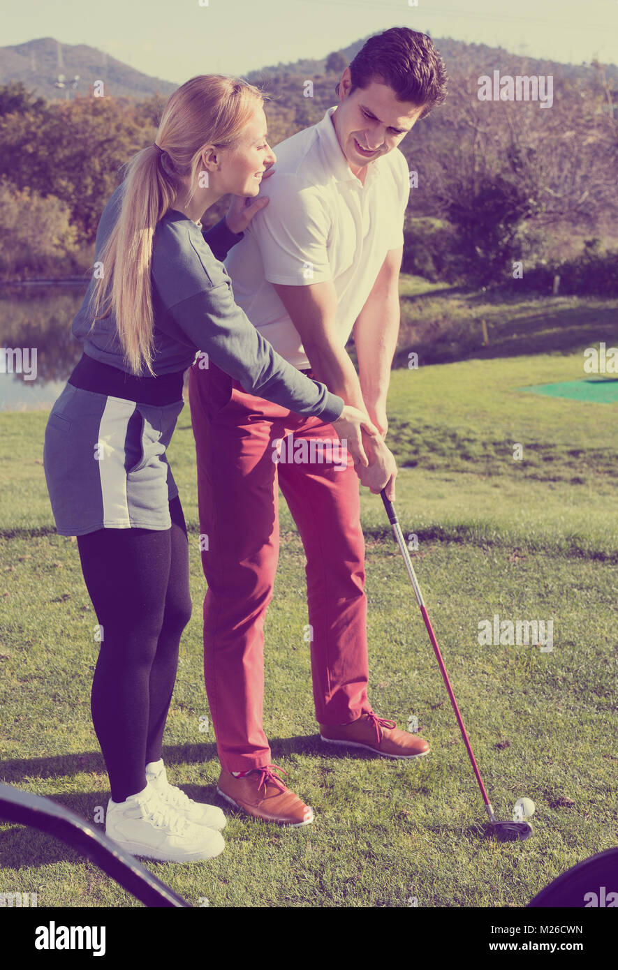 Piuttosto golf trainer che mostra il lettore maschio come colpire giustamente a sfera Foto Stock