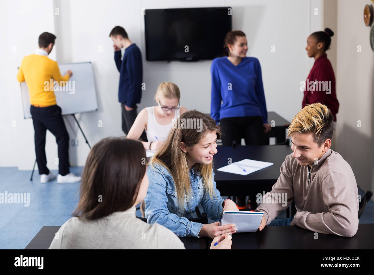 Ragazza sorridente consulting studente borsista durante le prove di esame in aula Foto Stock