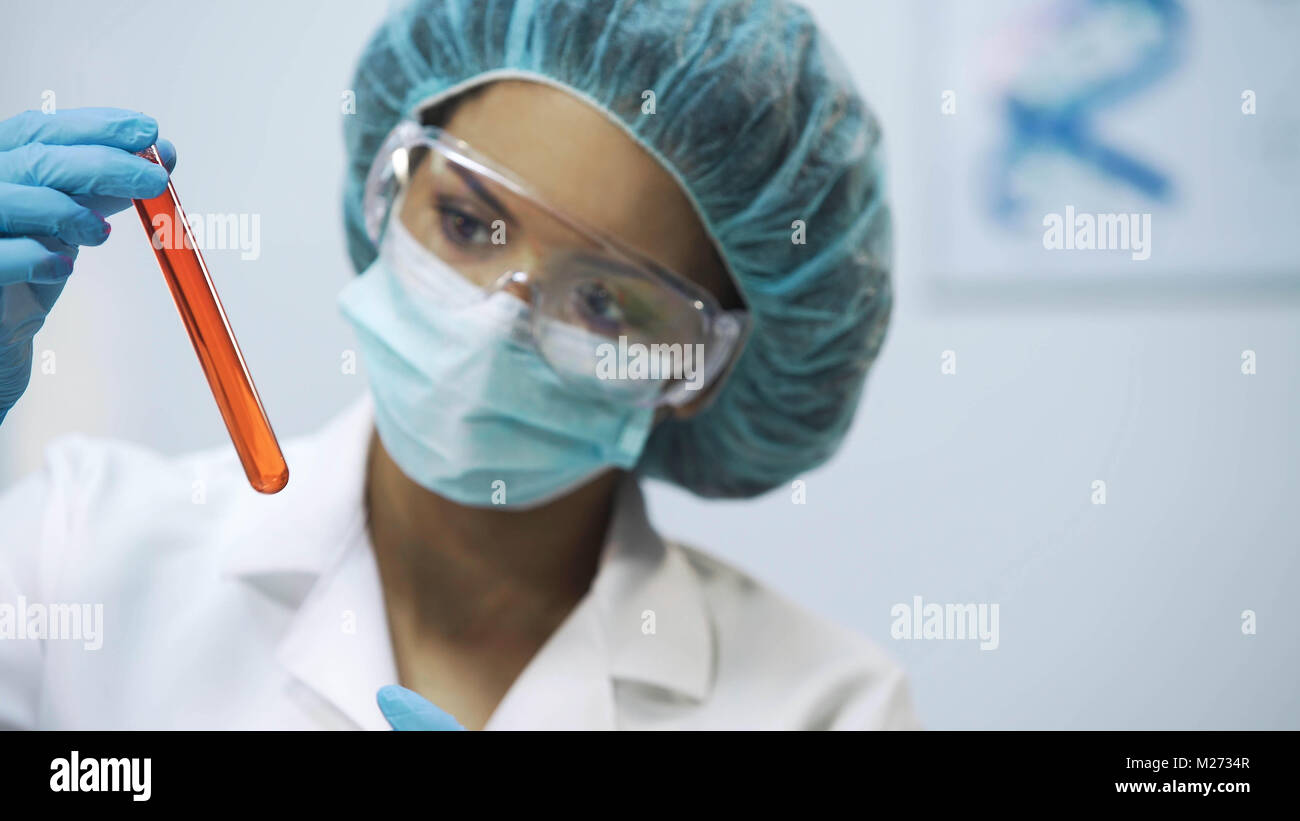 Mixed-gara praticante analizzando un nuovo vaccino liquido nel tubo, competenza medica Foto Stock
