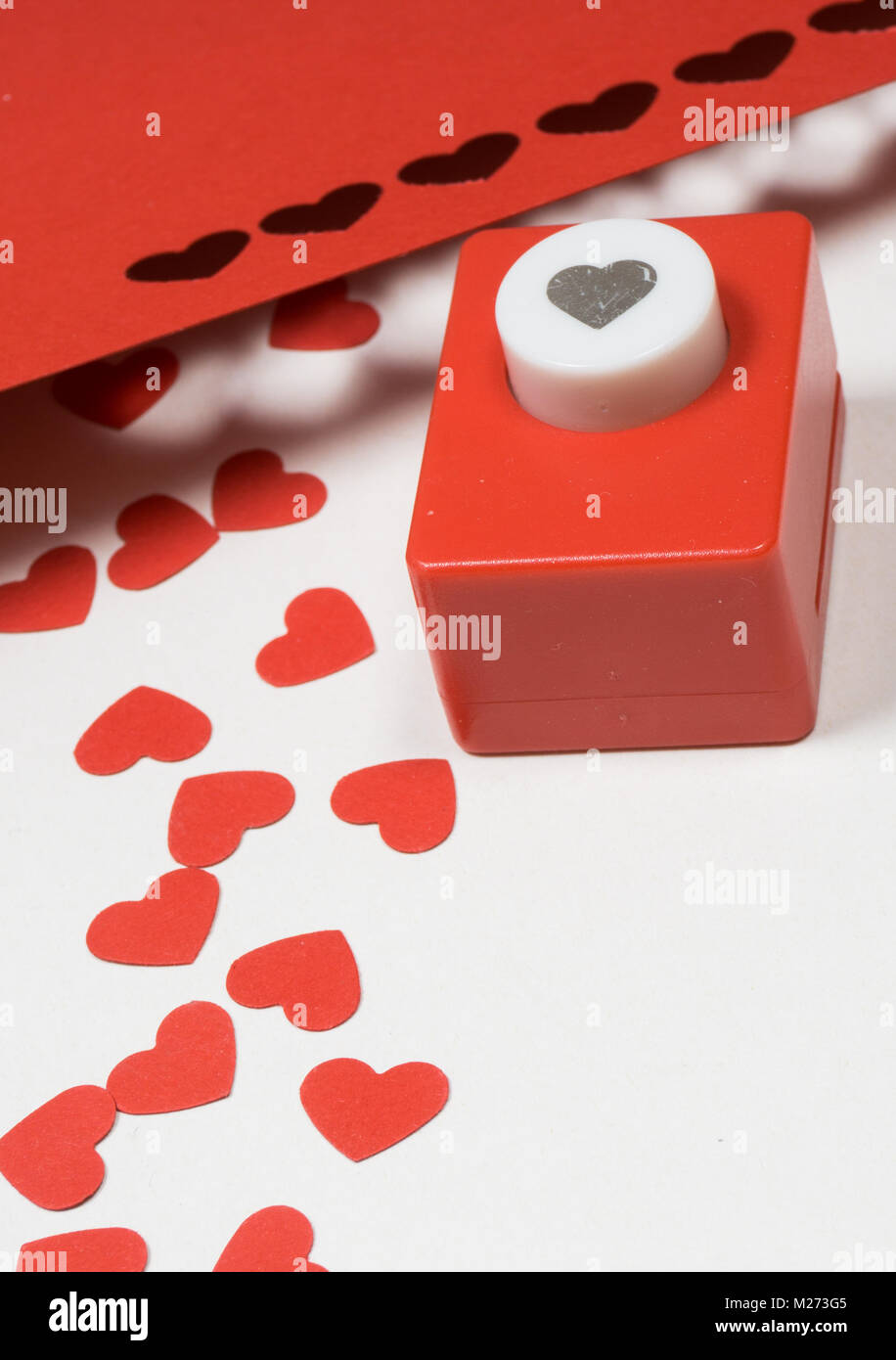 Decorazione per il giorno di San Valentino: perforatrice di carta  realizzato in forme di cuori rossi Foto stock - Alamy