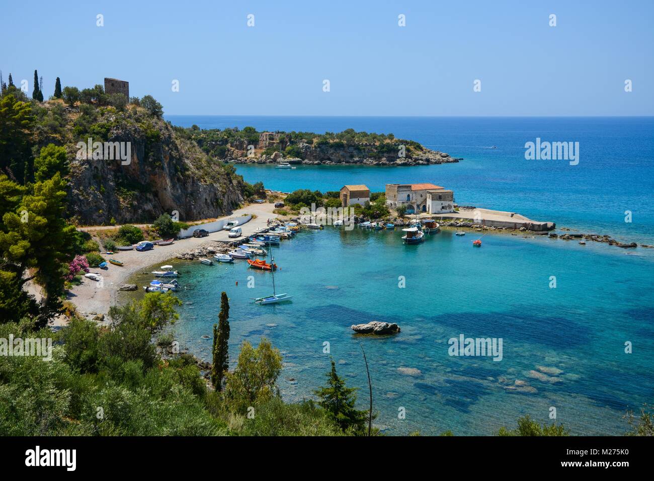 Idilliaco paesaggio di un grazioso porto greco con barche e degli edifici e limpido mare blu Foto Stock