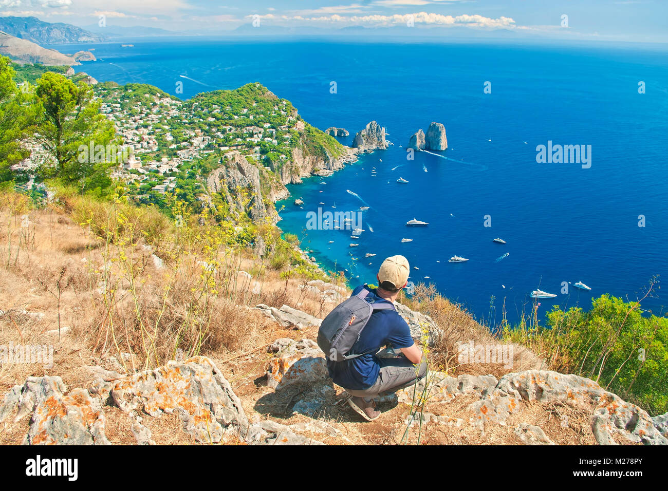 Persona che viaggia da sola riposo dopo la salita Monte Solaro si affaccia su famosi faraglioni sulla soleggiata giornata estiva, Capri, Italia Foto Stock