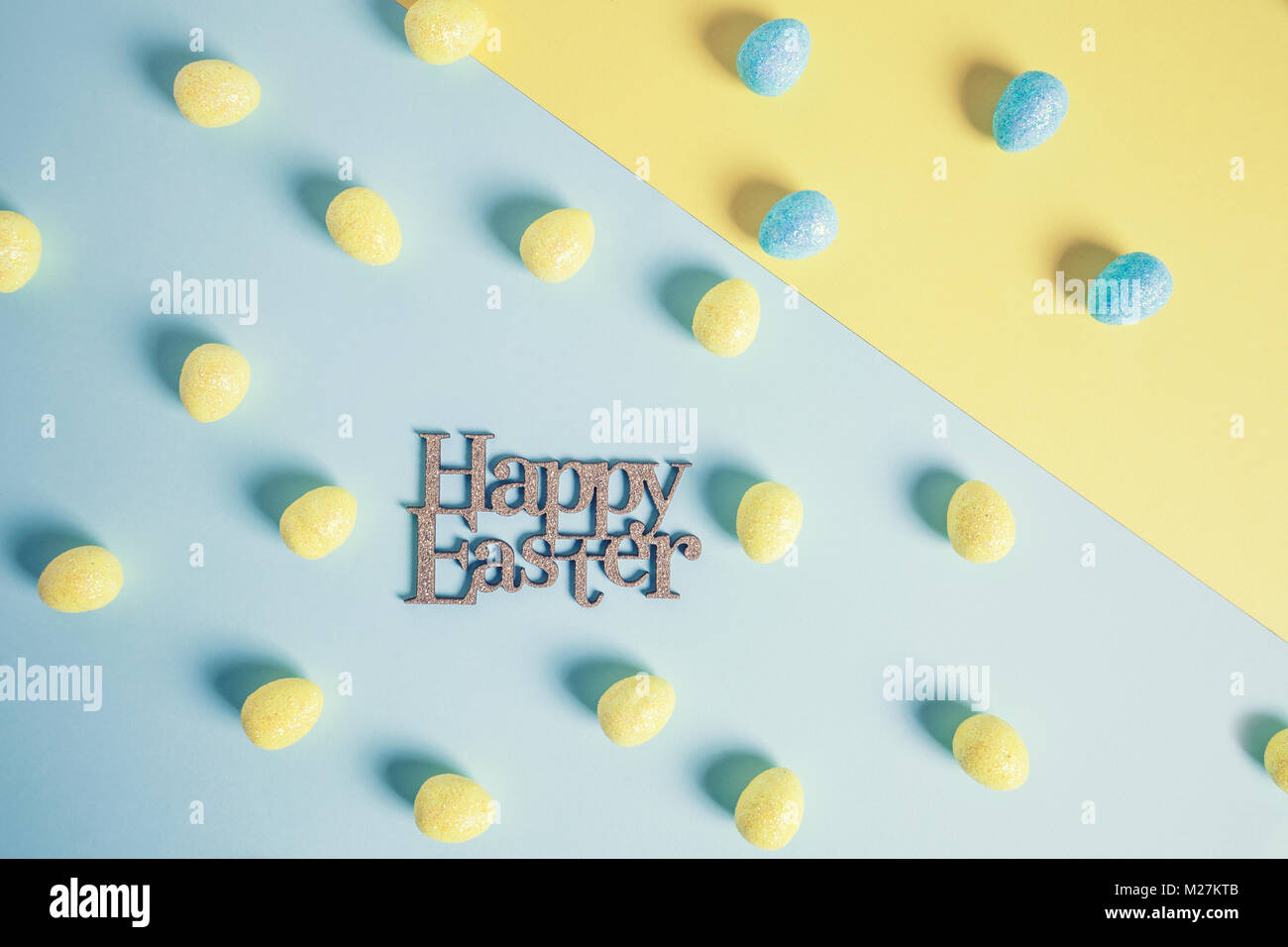 Felice Pasqua design con i colori giallo e blu glittery uova di pasqua su carta. Il minimo di colore pastello concept Foto Stock