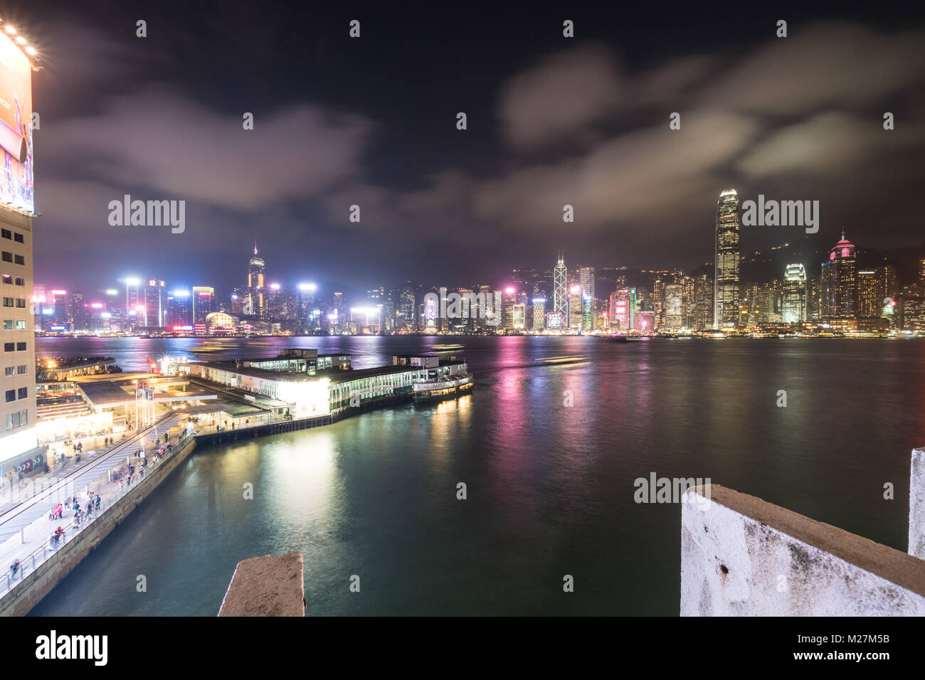 Hong Kong - 25 Gennaio 2018: lo Star Ferry Terminal in Tsim Sha Tsui in Kowloon con l'isola di Hong Kong famoso skyline notturno su Victoria h Foto Stock