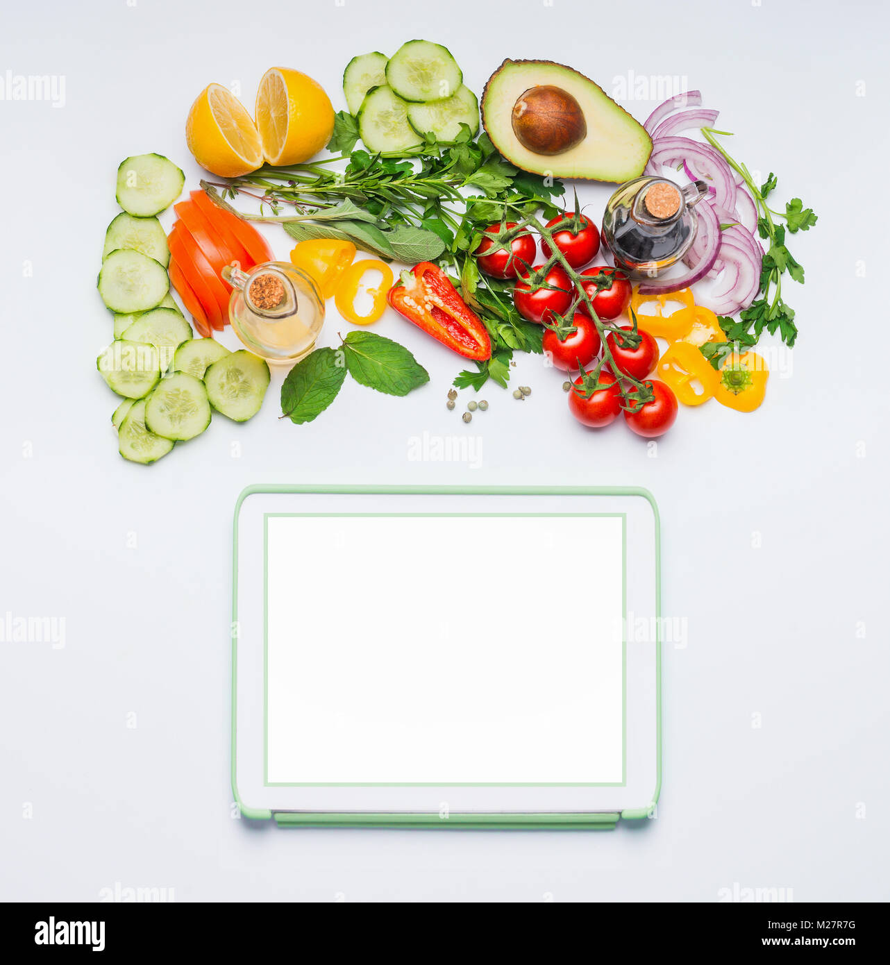 Varie fresche verdure organiche per una gustosa insalata estiva e tablet mock up su sfondo bianco, vista dall'alto. La cucina moderna, mangiare e dieta concetto. Foto Stock