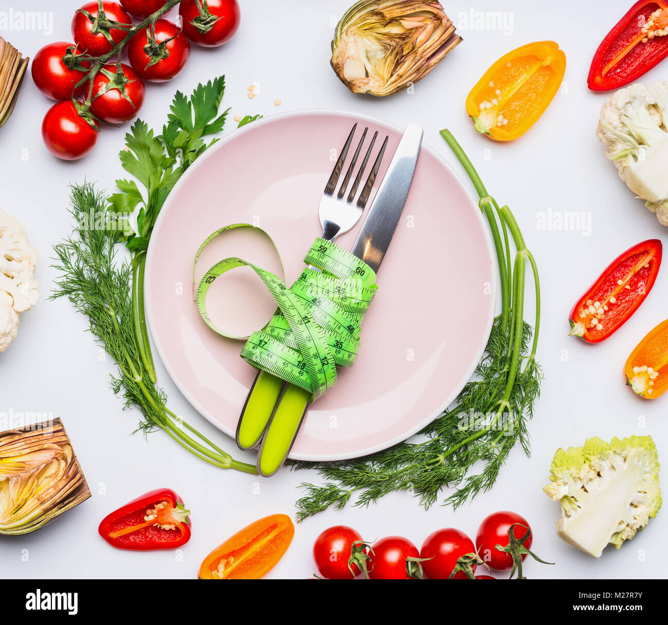 Cibo sano e dieta concetto. Piastra con posate e nastro di misurazione sul tavolo con verdure su sfondo bianco, vista dall'alto Foto Stock
