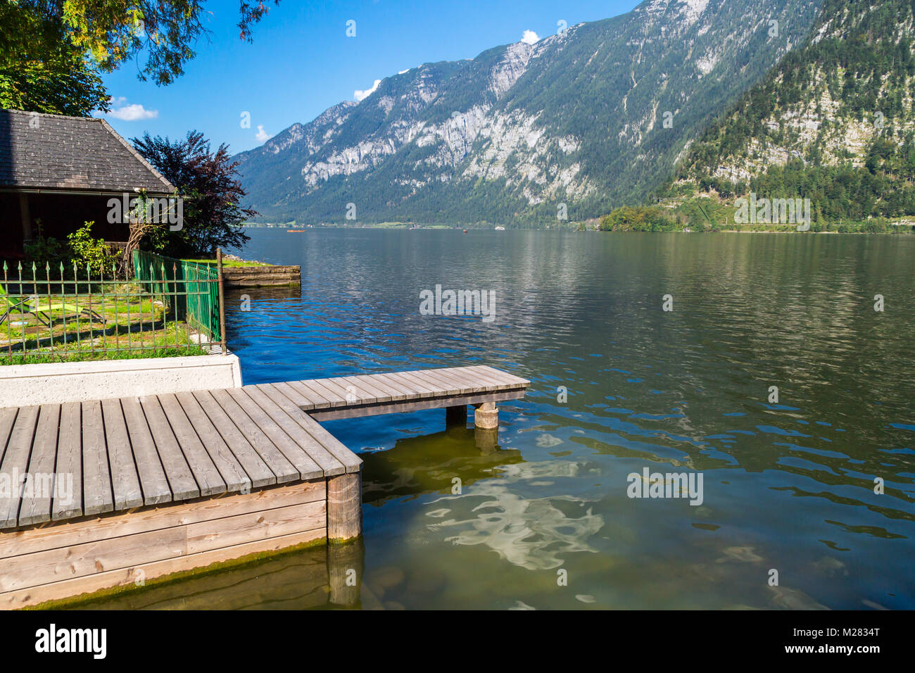 Vista del paesaggio del lago Hallstatt, noto anche come Hallstatt vedere, con un molo di acqua chiara tra alte montagne di alp. Foto Stock