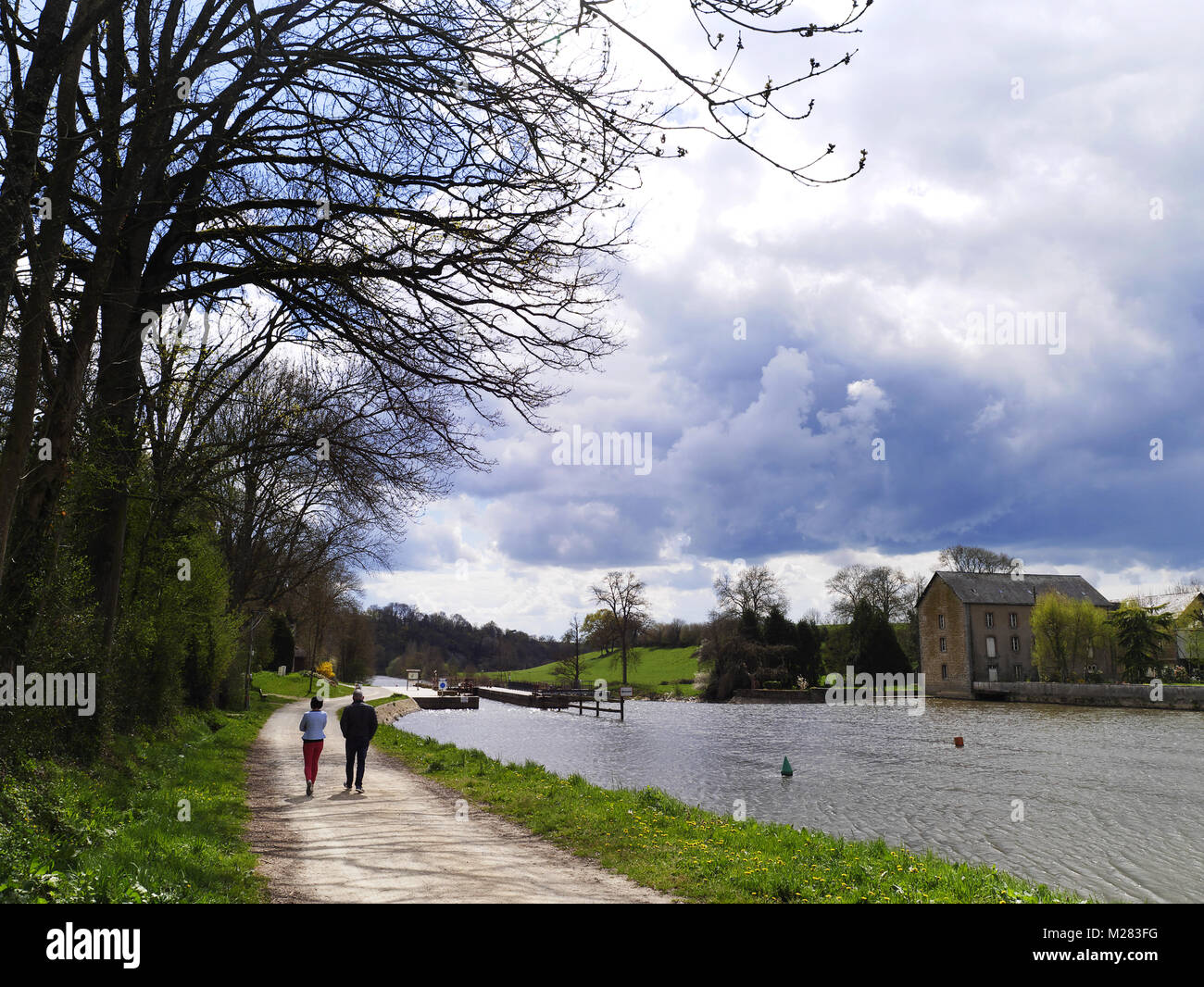 Alzaia lungo un fiume, un giovane è a piedi, fiume la Mayenne in aprile (Saint Baudelle, dipartimento Mayenne, Paese della Loira, Francia). Foto Stock