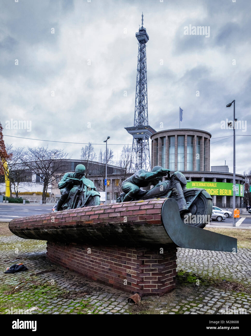 Berlin-Westend, scultura in bronzo di due moto piloti. Un monumento per i motociclisti con Berliner Funkturm torre della radio & trade fair center building Foto Stock