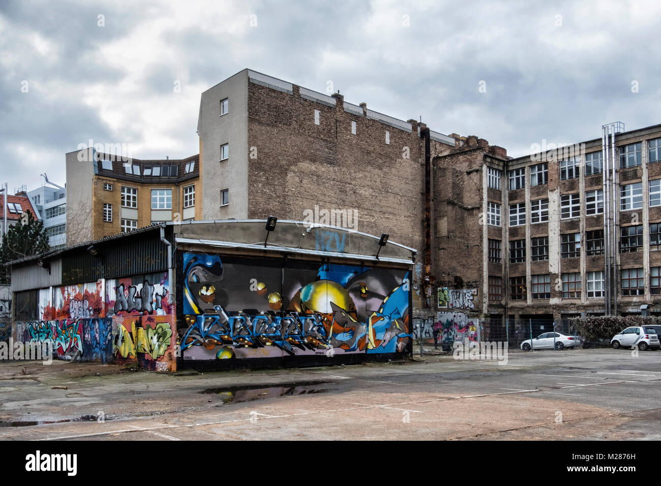 Berlino, Prenzlauerberg, Graffiti magazzino coperto ebetween dilaipdated edifici a Schönhauser Allee Foto Stock