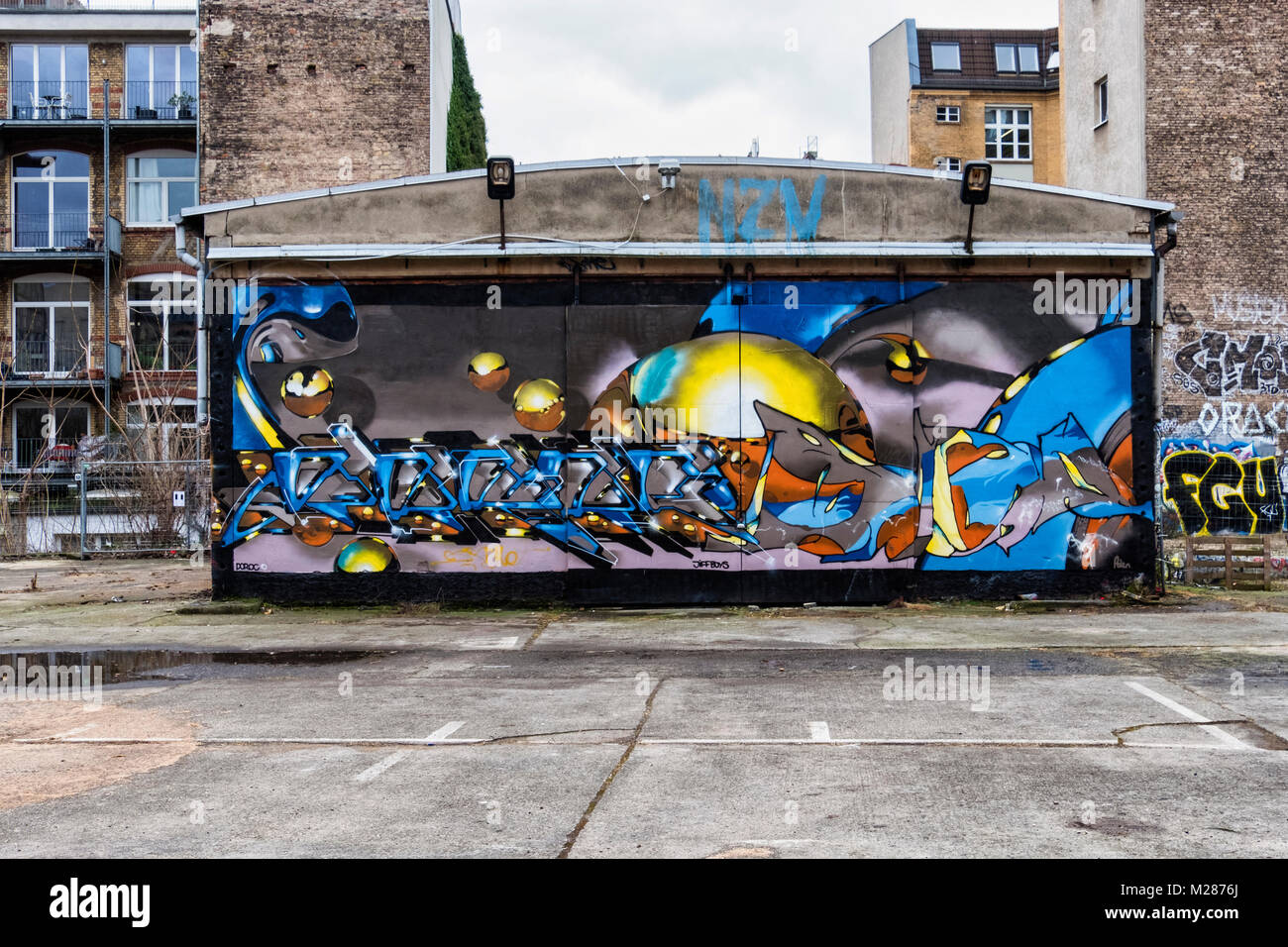 Berlino, Prenzlauerberg, Graffiti magazzino coperto tra edifici dilaipdated in Schönhauser Allee Foto Stock
