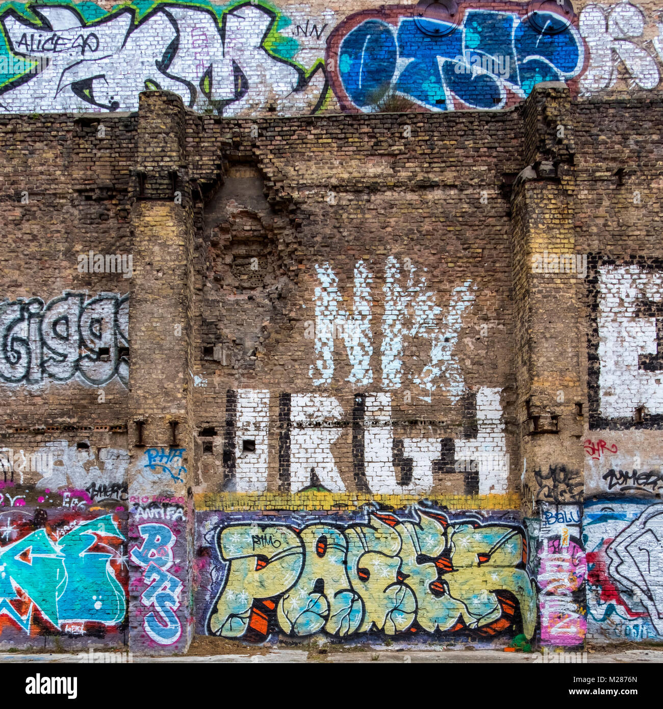 Berlino, Prenzlauerberg, coperto di graffiti fatiscenti sbriciolare un muro di mattoni sul vecchio edificio in Schönhauser Allee. Foto Stock