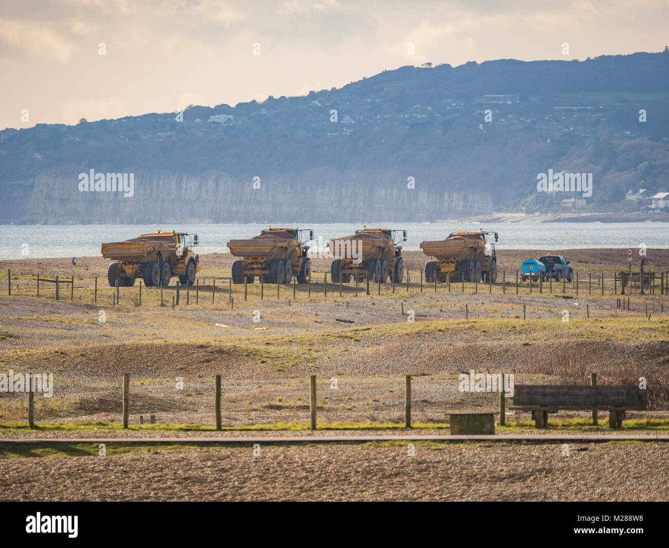 Convoglio di autocarri con cassone ribaltabile sulla costa di segale di scandole in movimento Foto Stock