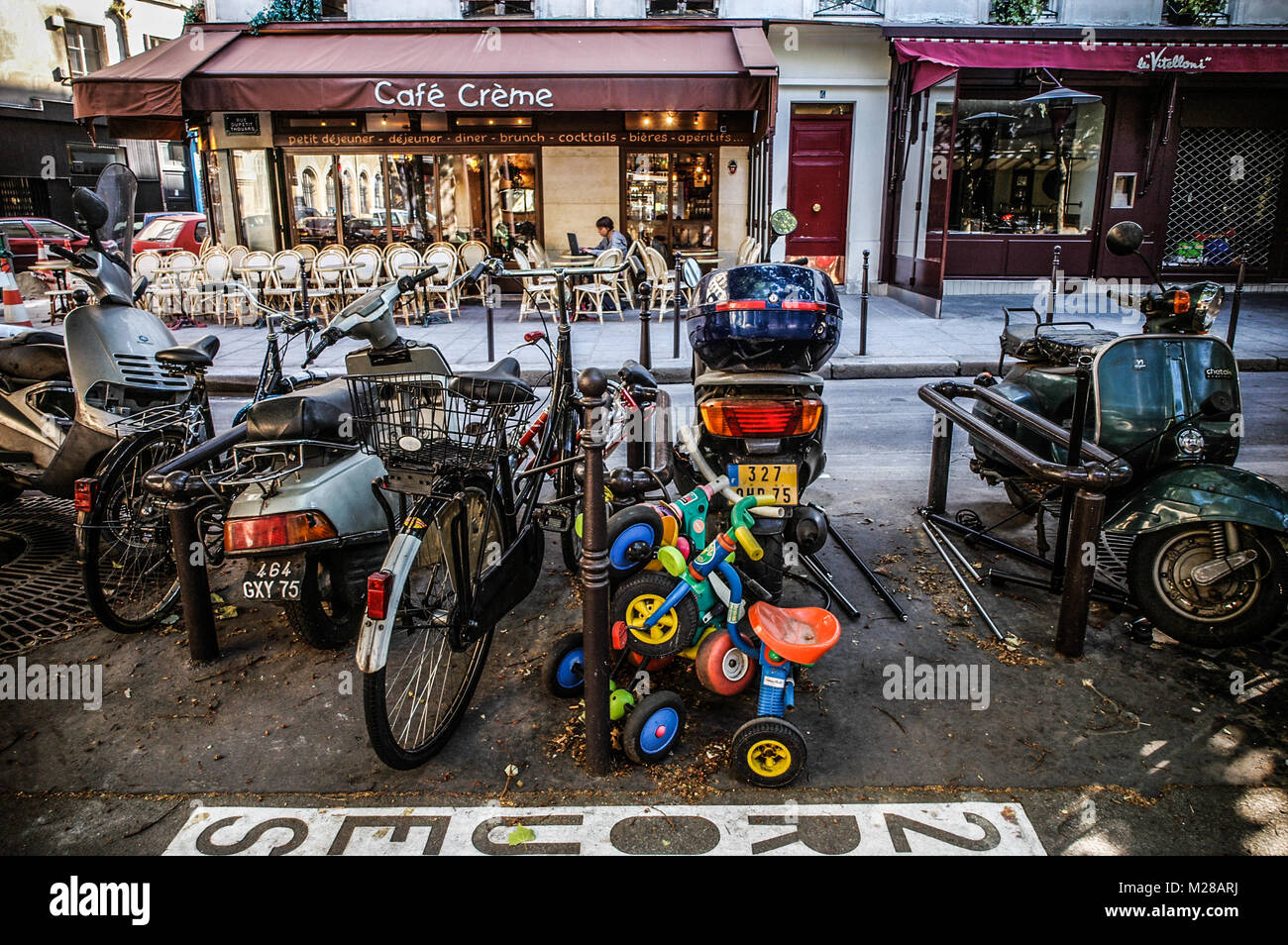 Parigi due ruote parcheggio in strada - SCOOTER, adulti e bambini biciclette nei pressi di un Cafe - Via Parigi - PARIS CAFE - Francia © Frédéric BEAUMONT Foto Stock