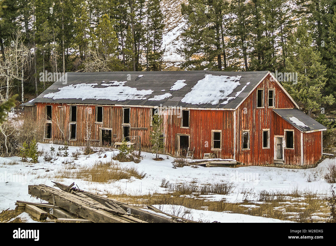 Il vecchio edificio rosso con vernice sbiadita e un tar tetto della carta Foto Stock