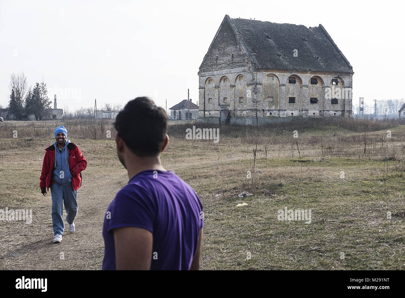 Horgos, Kanjiza, Serbia. 27th Jan, 2018. Migrants from Pakistan walk past a large building were they are living close to the Serbian - Hungarian border. Horgos is a village located in Kanjiza municipality, in the North Banat District of Serbia, less than 10km from the Serbian Ã Hungarian border. The Balkan route was officially closed over a year ago with Croatia and Hungary increasing border security which has led to migrants and refugees becoming stuck in Serbia. While the borders around Serbia have tightened there are still attempted border crossings every night. Migrants from Pakist Foto Stock