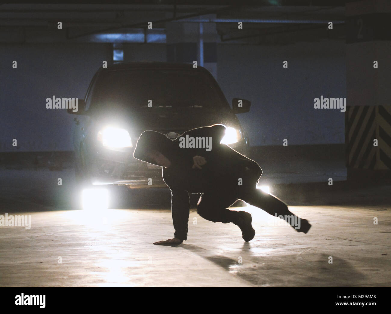 L'uomo freerunner lato facendo capriole in garage, parkour elementi acrobatico Foto Stock
