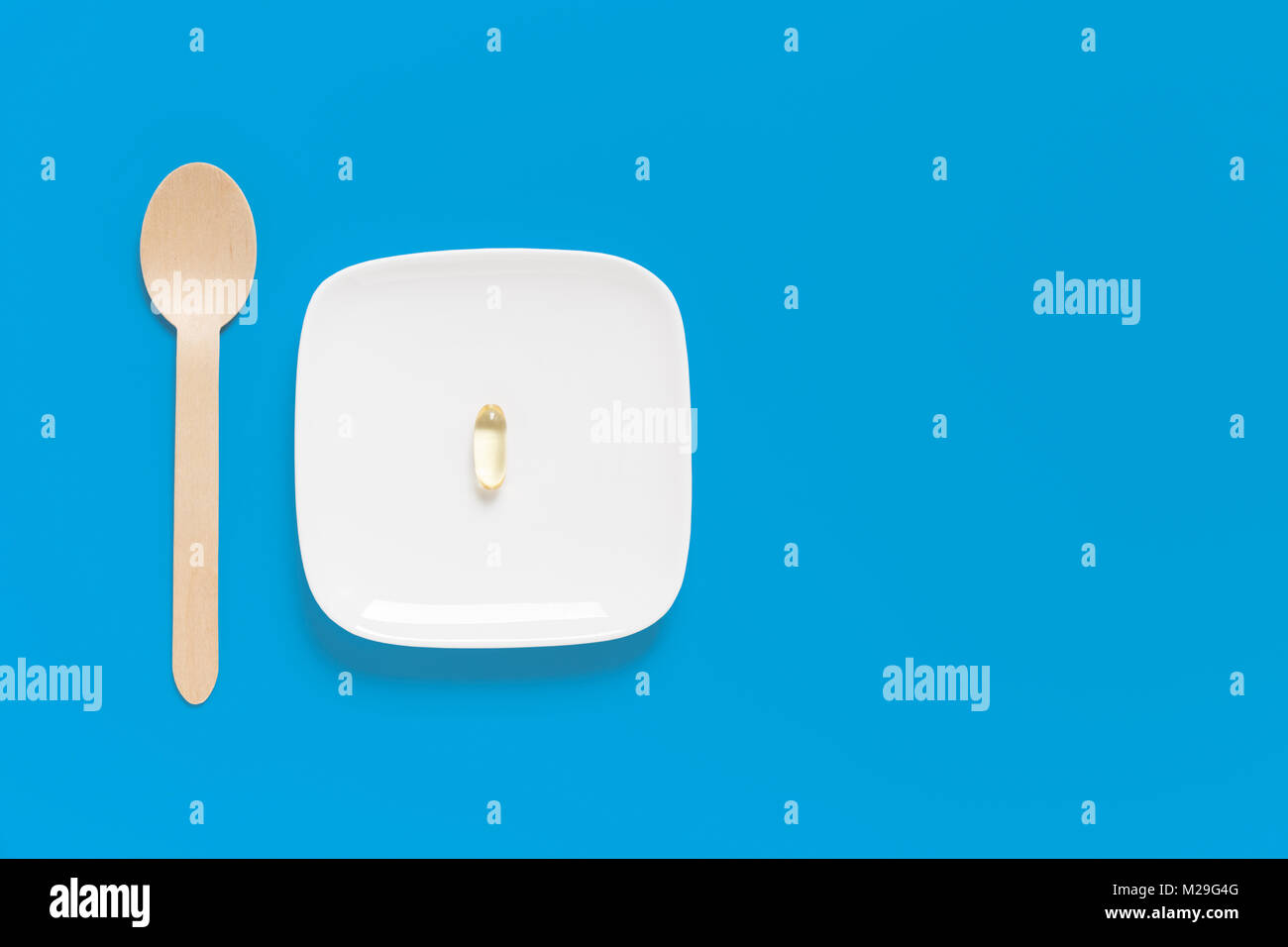 Olio di pesce capsule sulla piastra con cucchiaio contro uno sfondo blu Foto Stock