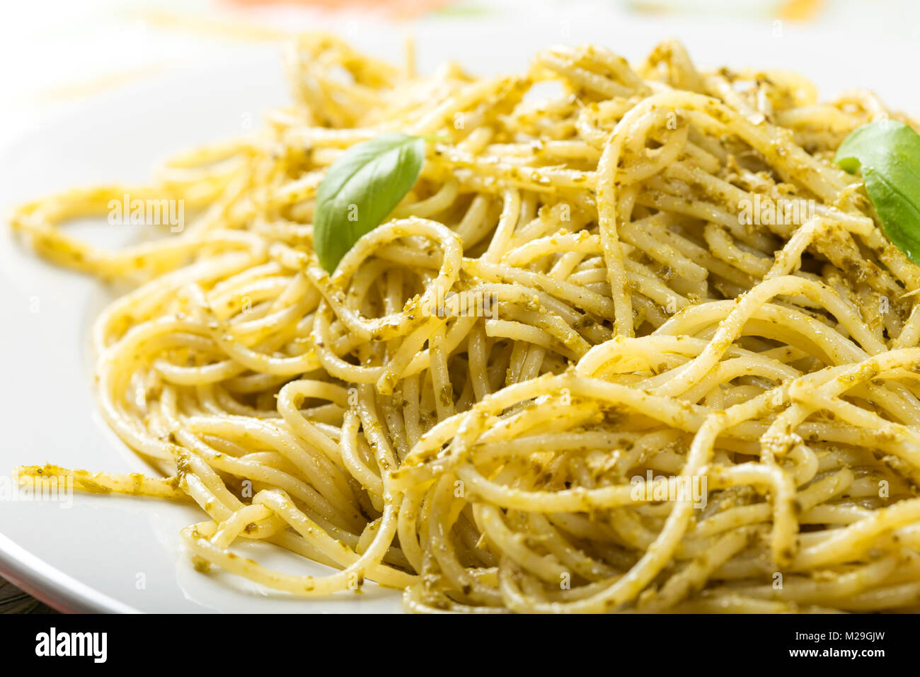 Spaghetti con fatti in casa al pesto di olio di oliva con le foglie di basilico sulla piastra bianca Foto Stock