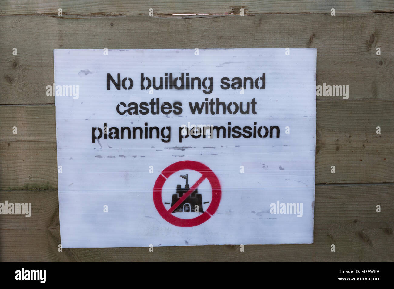 Divertente scherzo segno sulla spiaggia a Swansea dicendo no costruire castelli di sabbia senza il permesso di pianificazione Foto Stock