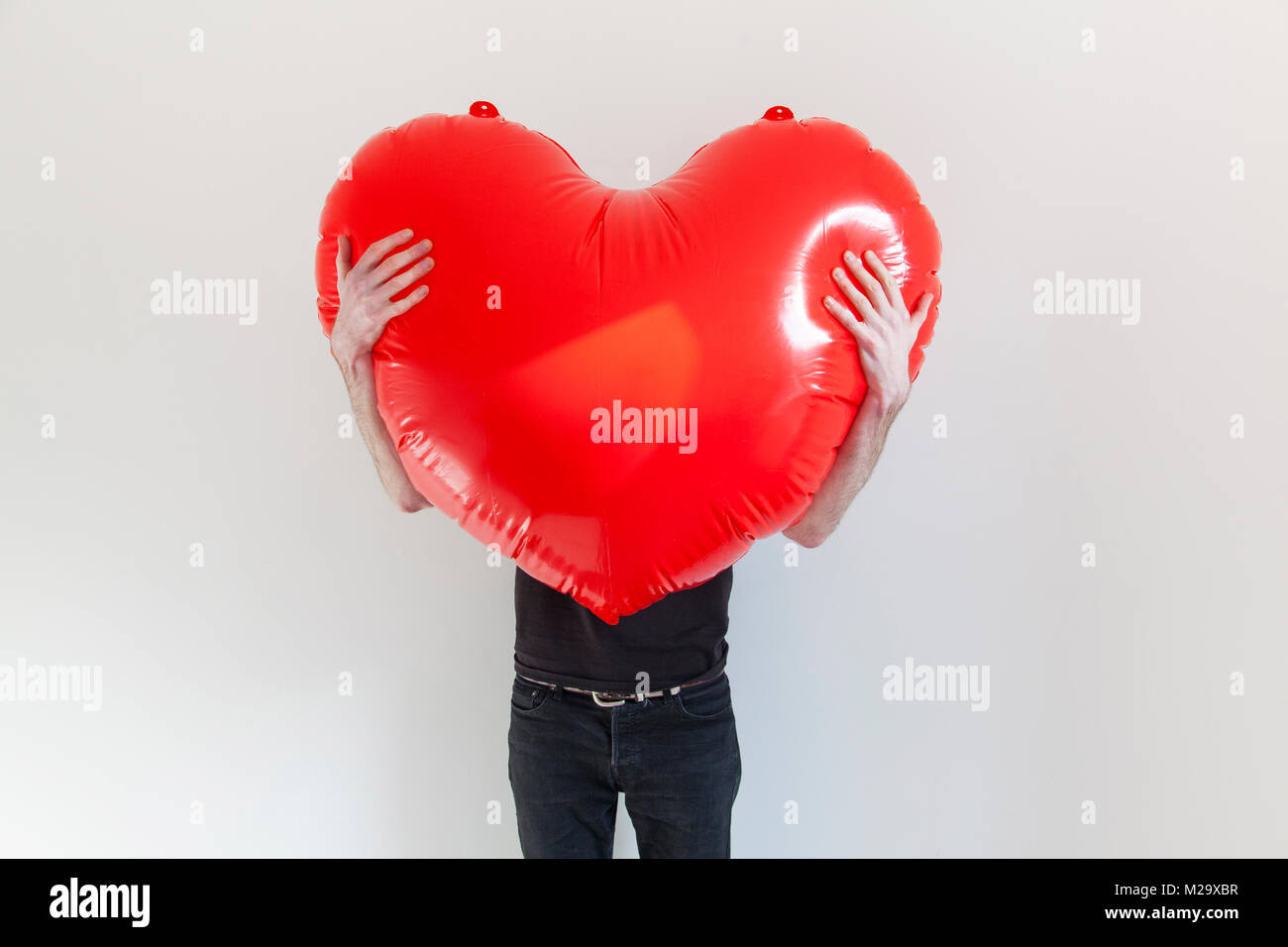 Una persona che abbraccia una grande rosso amore gonfiabile cuore. La salute e il concetto di amore Foto Stock