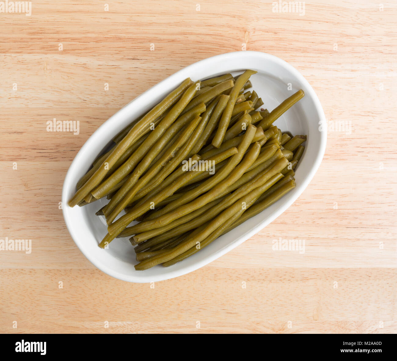 Vista superiore del gourmet marinate fagioli verdi in un ovale piatto di cottura su un bancone di legno. Foto Stock