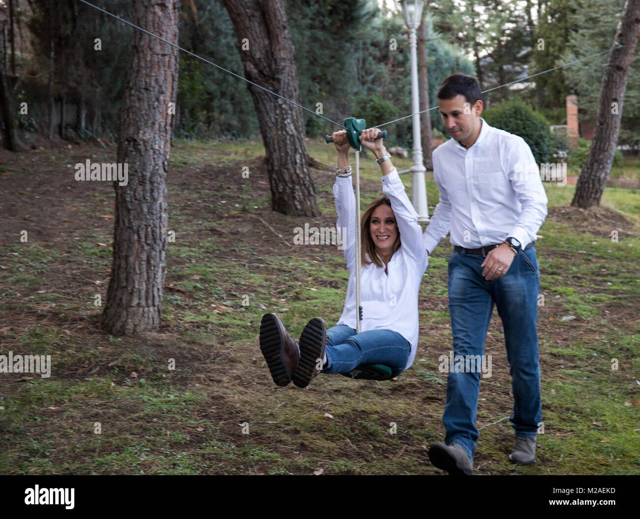 Abbigliamento casual giovane riproduce in un zip line nel giardino della loro casa Foto Stock