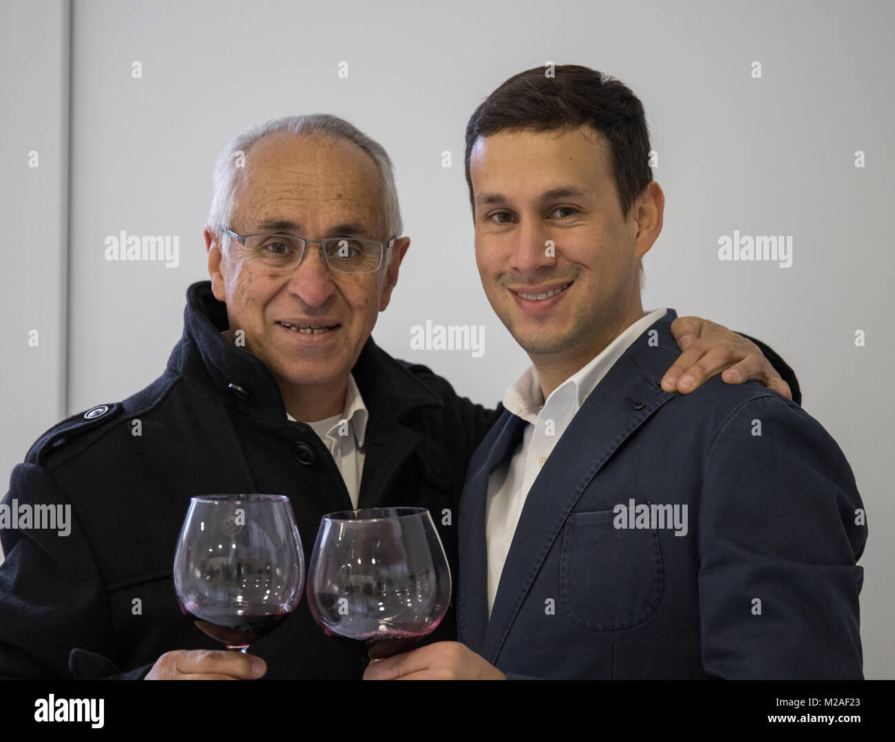 Padre e figlio di bere un bicchiere di vino in cucina a casa Foto Stock