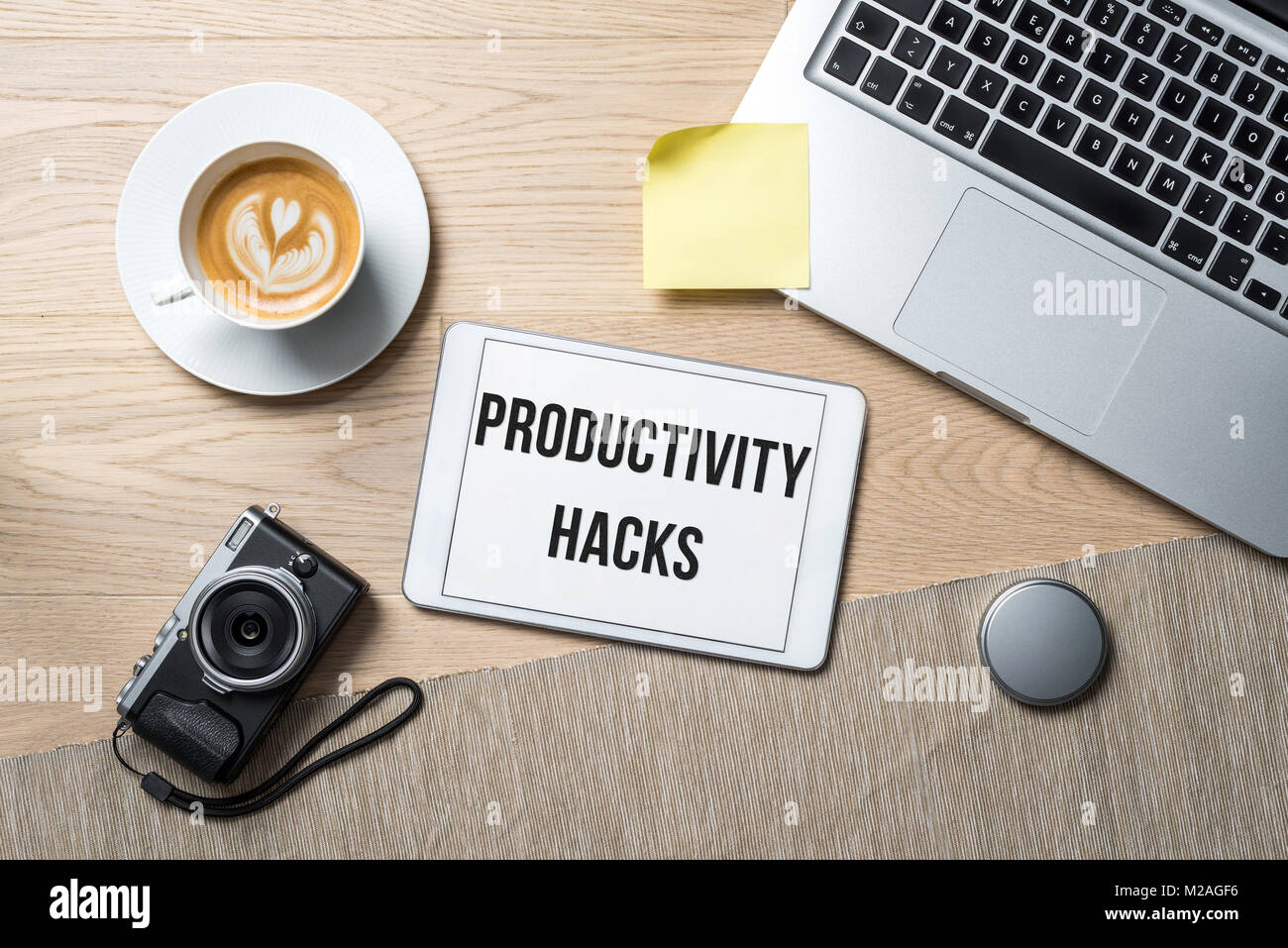 Produttività hacks la scrittura su tablet con fotocamera, tazza da caffè e laptop giacente sulla fotografia scrivania in ufficio come laici piatta Foto Stock