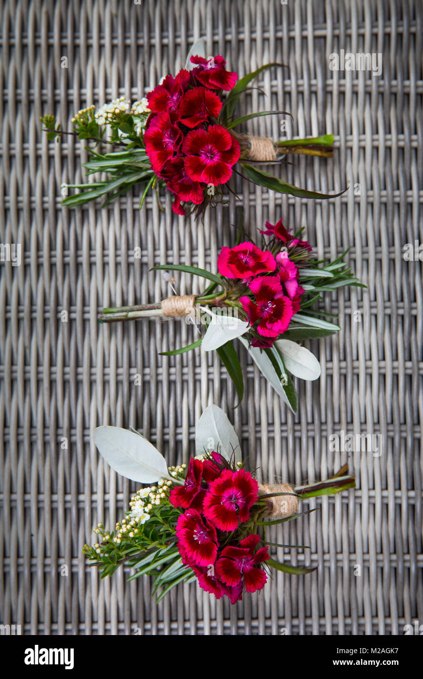 Tre rosa boutonnieres matrimonio su wickwork, vista aerea Foto Stock