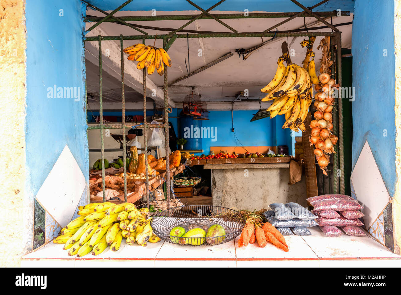 Una apertura di finestra con barre di ferro, per la vendita di frutta e verdura, cipolle, banane, carote Foto Stock