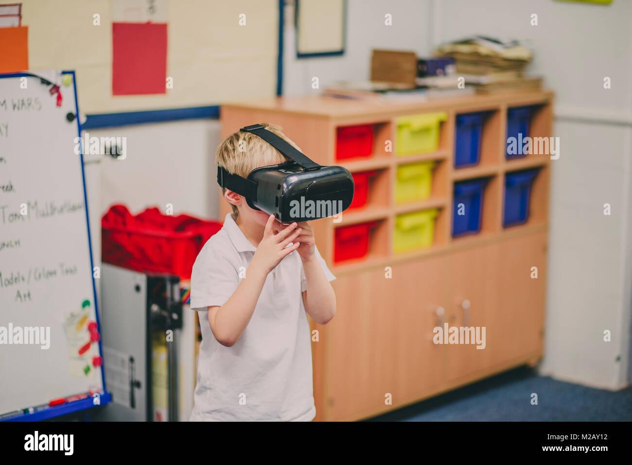 Little Boy sta sperimentando con la realtà virtuale in aula a scuola. Foto Stock