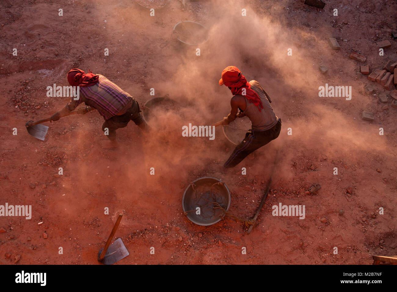 Gli uomini raccolgono polvere nella base della fabbrica di mattoni in Nepal. Foto Stock