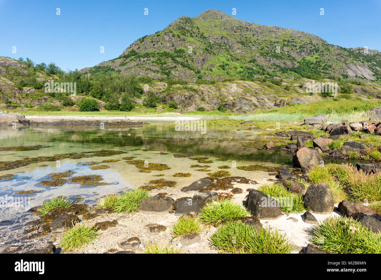 L'acqua turchese, verdi colline e pietre, arcipelago delle Lofoten, Norvegia, Arsteinen isola Foto Stock