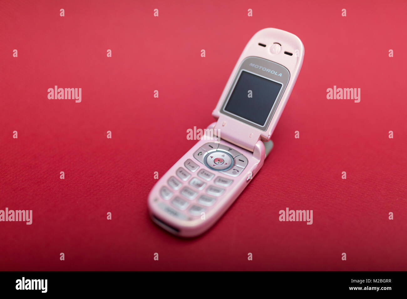 Raffreddare e classic Motorola V220 rosa flip retrò cellulare o telefono cellulare isolata contro uno sfondo rosso Foto Stock