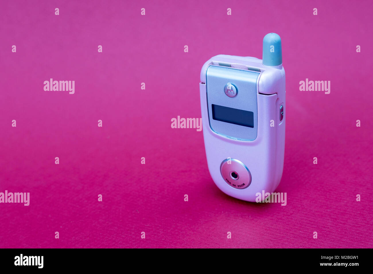 Raffreddare e classic Motorola V220 rosa flip retrò cellulare o telefono cellulare isolata contro uno sfondo rosso Foto Stock