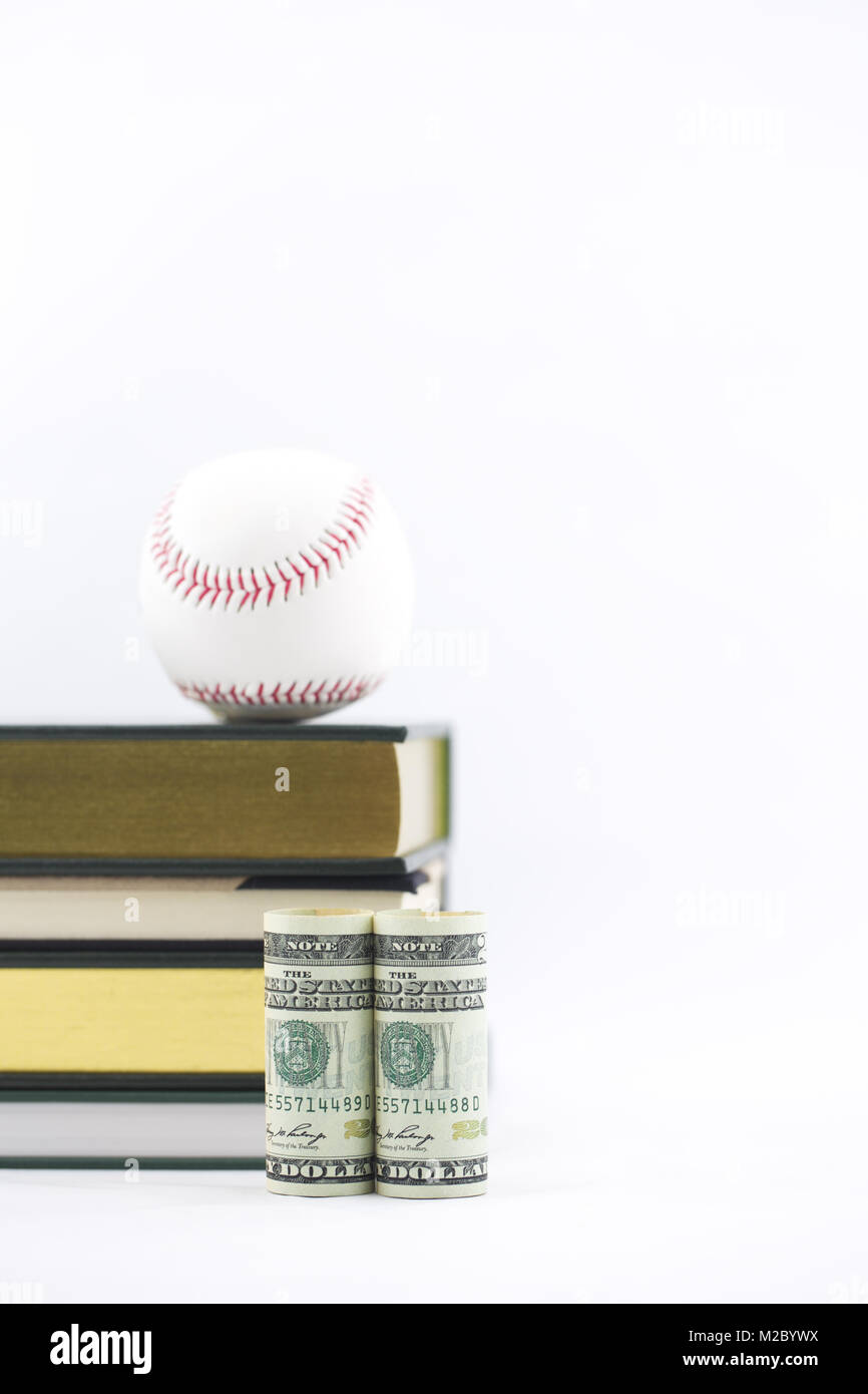 Il baseball si siede sui libri con moneta americana nella parte anteriore Foto Stock