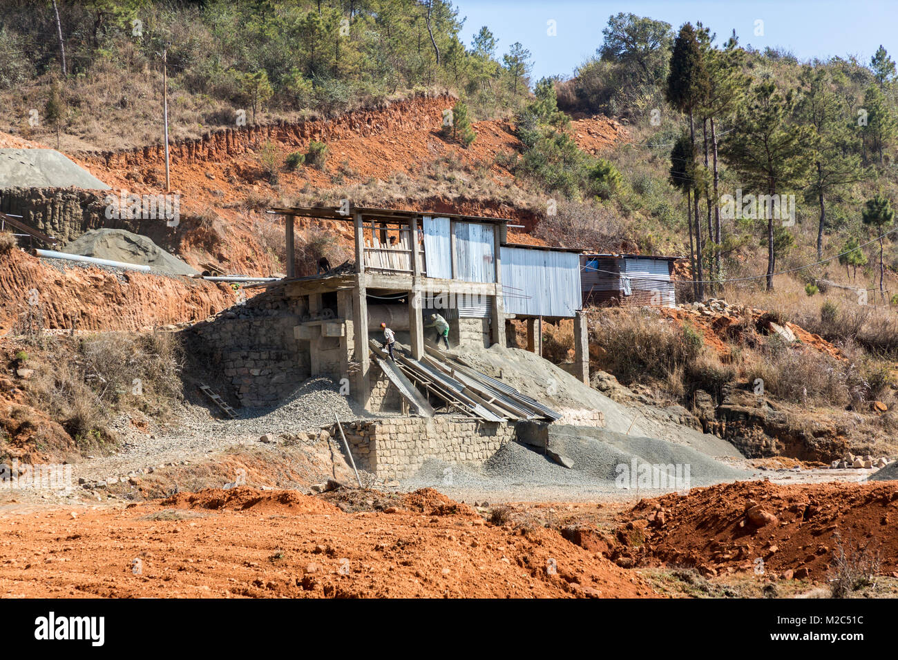 Uomini al lavoro in un frantoio in pietra per creare la ghiaia, in modo da Mawsynram a Shillong, Meghalaya, India Foto Stock