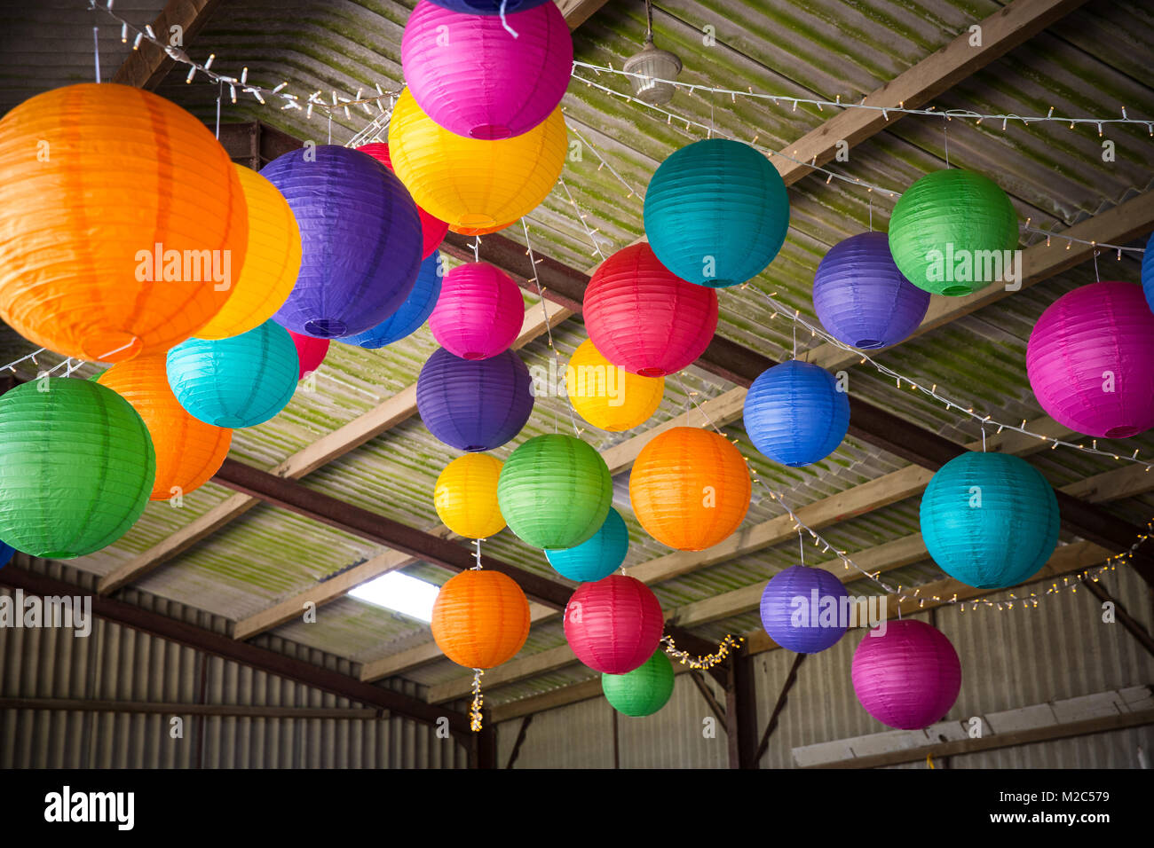 Carta colorata lanterne pendenti dal soffitto del granaio Foto Stock