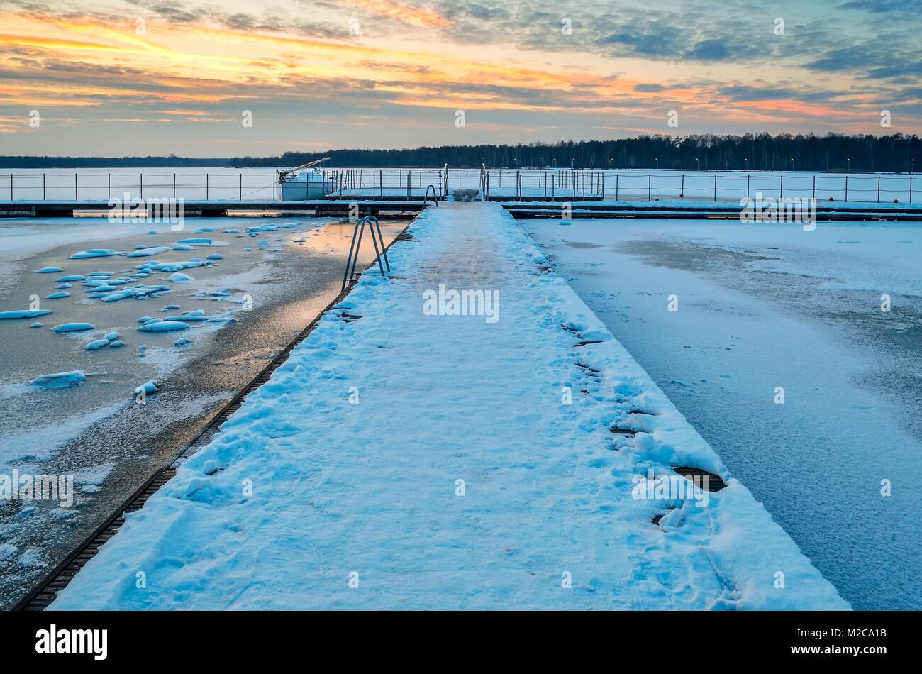 Pomeriggio paesaggio invernale. Un molo su un bellissimo lago ghiacciato. Foto Stock