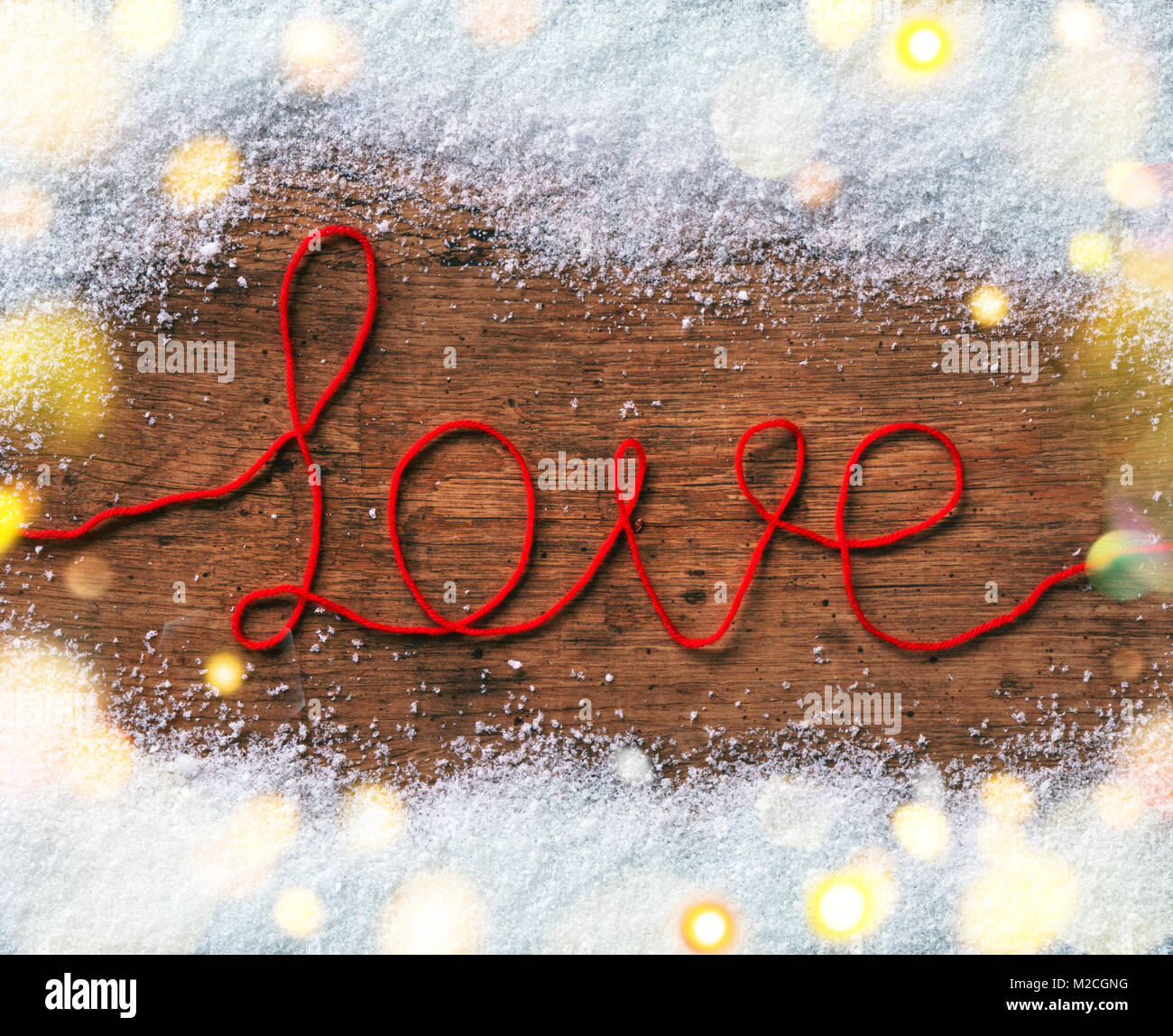 La parola 'amore' su sfondo di legno con la neve. Vista dall'alto. Il giorno di San Valentino concetto Foto Stock